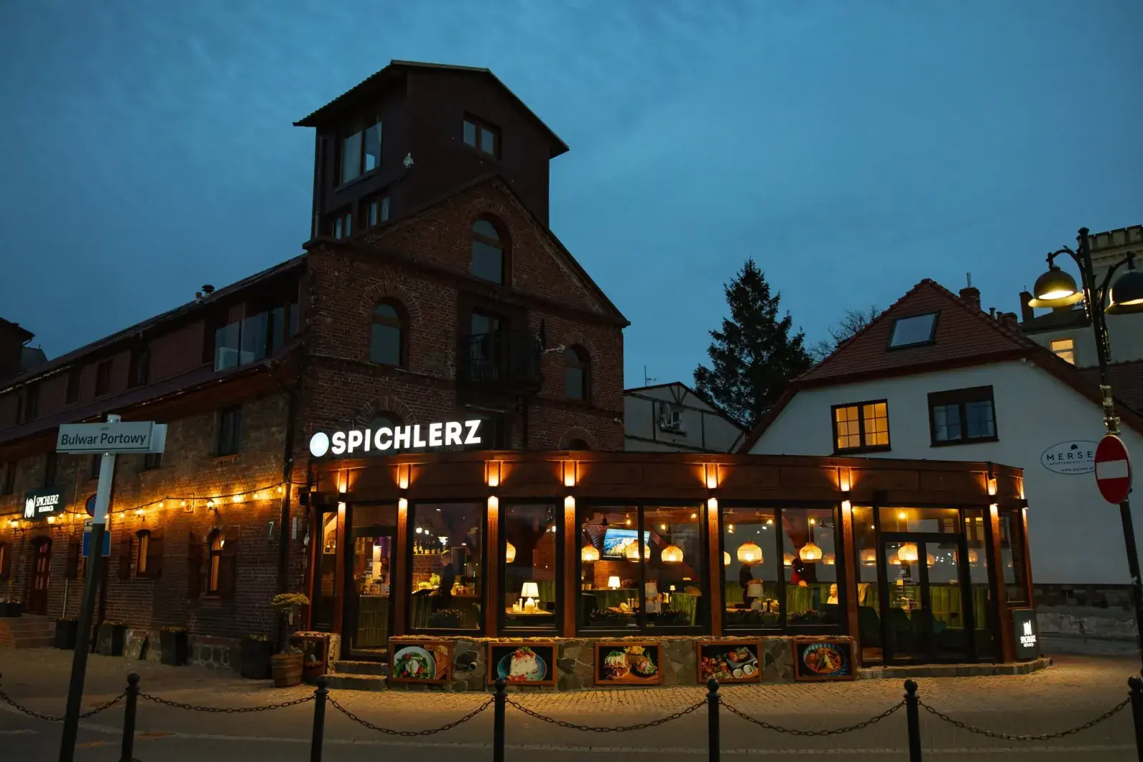 Restauracja Spichlerz wieczorem, podświetlony przeszklony pawilon na rogu Bulwaru Portowego